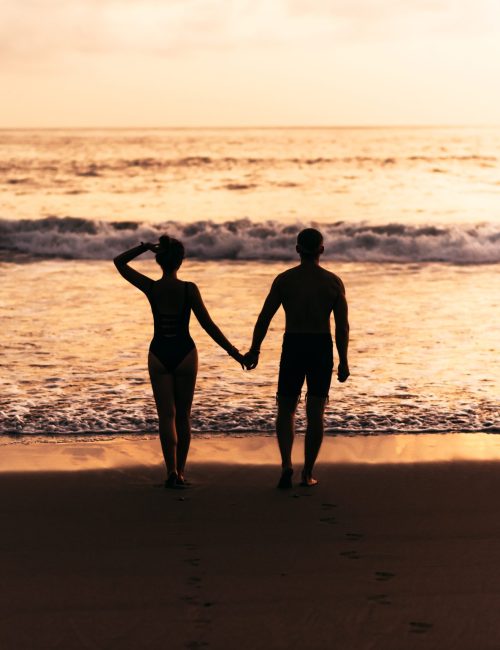 Silhouette of loving couple on sea. A couple in love at sunset. Man and woman meet sunset. Happy loving couple. Silhouette lovers. Man and woman watching the sunset. Hold hands